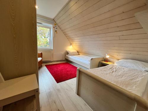 Habitación pequeña con 2 camas y alfombra roja. en Haus Moby Dick, en Wangerooge
