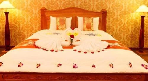 a bed with white sheets with bees on it at New Palace Bac Lieu Hotel in Bạc Liêu