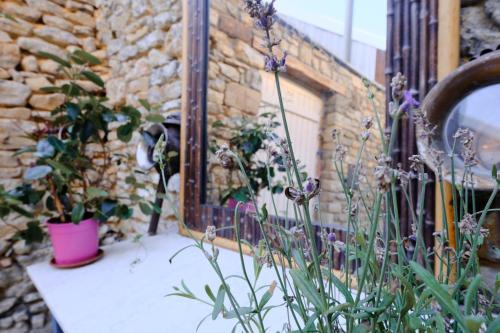 a balcony with flowers and a stone wall at LOGIS des COEVRONS in Évron