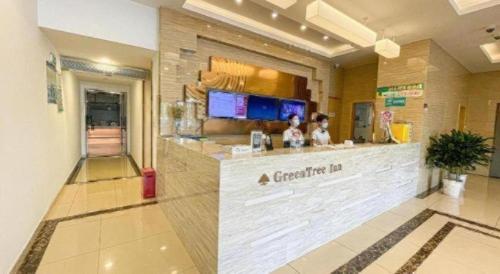 a bar in a restaurant with a woman standing at a counter at GreenTree Inn Shanghai National Convention and Exhibition Center Huaxiang Road in Shanghai
