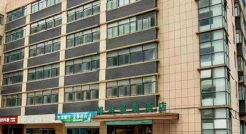 a tall building with a street sign in front of it at GreenTree Inn Shanghai National Convention and Exhibition Center Huaxiang Road in Shanghai
