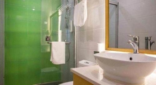 a green and white bathroom with a sink and a shower at GreenTree Inn Shanghai National Convention and Exhibition Center Huaxiang Road in Shanghai