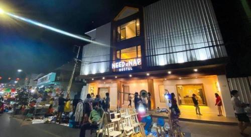 a group of people standing outside of a store at night at Need a Nap Hostel Phrae in Phrae
