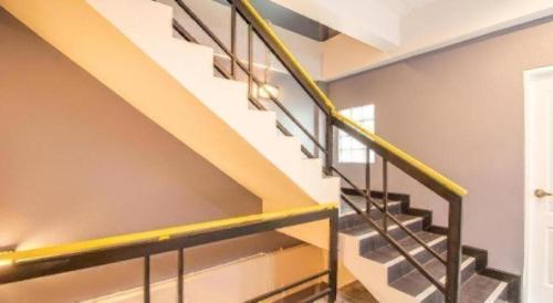 a metal staircase with yellow railing in a house at OYO 726 Sookjai Cafe and Hostel in Chiang Mai