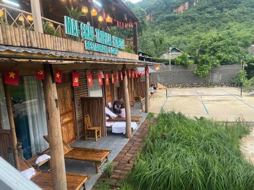 a restaurant with wooden chairs and a tennis court at Mai Chau Tropical Homestay in Hòa Bình
