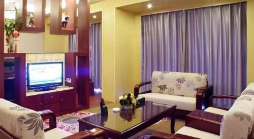 a living room with a couch and a tv at New Friendship Hotel in Luoyang