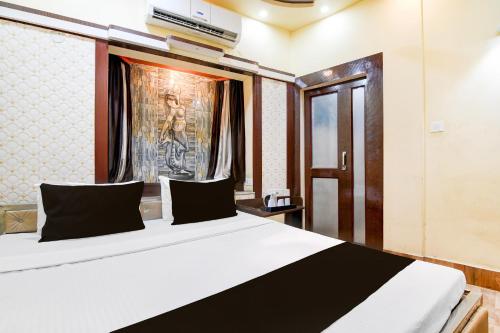 a bedroom with a large white bed with black pillows at Super Hotel O NIT Durgapur Formerly Royal Inn in Durgāpur
