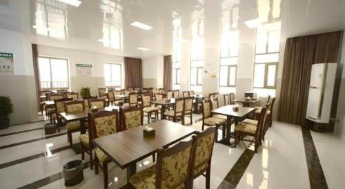 a dining room with tables and chairs and windows at GreenTree Inn Anhui Xuancheng Ningguo NinGYAng East Road Darunfa Branch in Xuanzhou