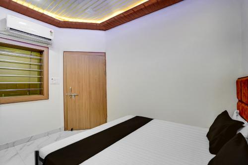 a bedroom with a bed with a window and a door at Super Hotel O Ugat Canal Surat Formerly Royal Orbit in Rānder
