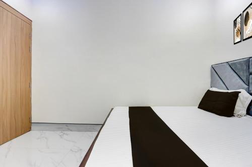 a bedroom with a white bed with black pillows at Super Hotel O Ugat Canal Surat Formerly Royal Orbit in Rānder
