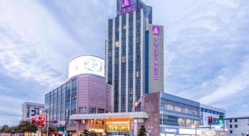 a tall building with a sign on top of it at Excemon Yuyao Hemudu Hotel in Ningbo