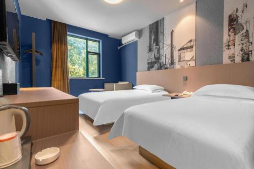 - une chambre d'hôtel avec 2 lits et des murs bleus dans l'établissement Jinjiang Inn Wenzhou Shuangyu The Terminal, à Wenzhou