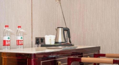 a table with a kettle and two bottles of soda at Metropolo Hotel Yining Development Zone Hanma Building in Kipekyüzi