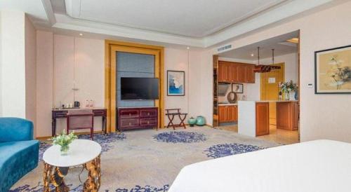 a living room with a blue couch and a kitchen at Metropolo Hotel Yining Development Zone Hanma Building in Kipekyüzi