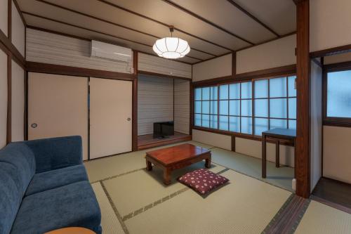 a living room with a blue couch and a table at OkutsuHotSpa IkedayaKajikaen in Kagamino