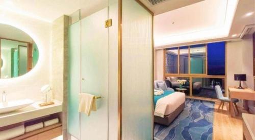 a bathroom with a bedroom with a bed and a sink at Emerald Bay Hotel in Yuxi