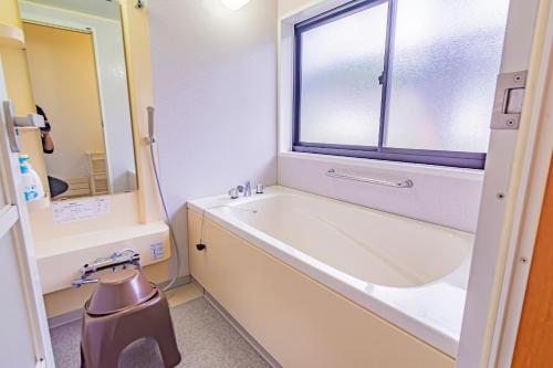a bathroom with a tub and a sink and a window at The Snowfront Apartment Nabe Sun -HAKUBA GORYU- in Hakuba