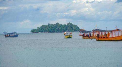 three boats in the water with an island in the background at Green Ocean Koh Rong in Koh Rong Island