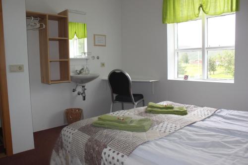 1 dormitorio con 1 cama y 2 toallas verdes en Guesthouse Hraunbaer, en Aðaldalur