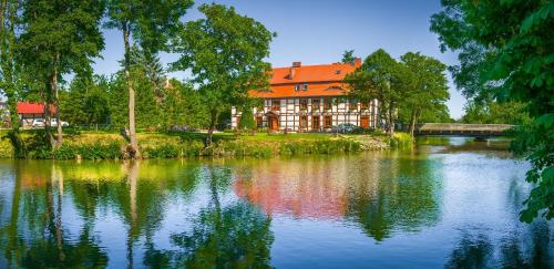 a building with an orange roof next to a lake at Gościniec Zamkowy in Darłowo