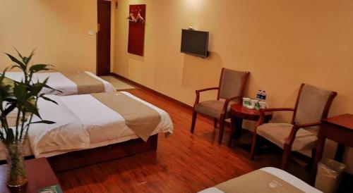 a hotel room with two beds and a table and chairs at GreenTree Inn Yixing Zhangzhu Express Hotel in Xinchating