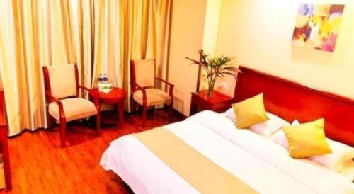 a hotel room with a bed and two chairs at GreenTree Inn Yixing Zhangzhu Express Hotel in Xinchating