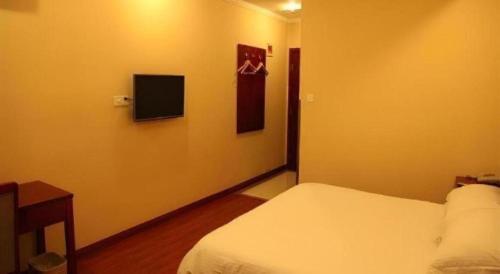 a bedroom with a bed and a tv on the wall at GreenTree Inn Yixing Zhangzhu Express Hotel in Xinchating