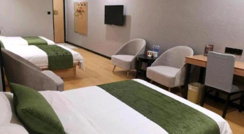 a room with three beds and chairs and a tv at GreenTree Inn Yixing Zhangzhu Express Hotel in Xinchating