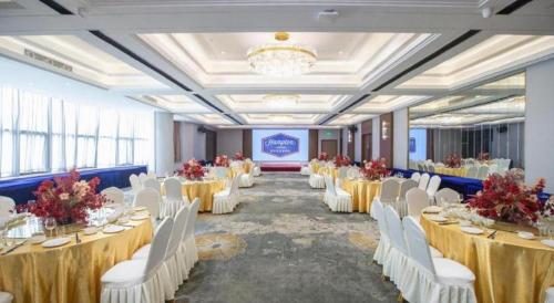 a banquet hall with white tables and white chairs at Hampton by Hilton Zhuhai Doumen in Zhuhai