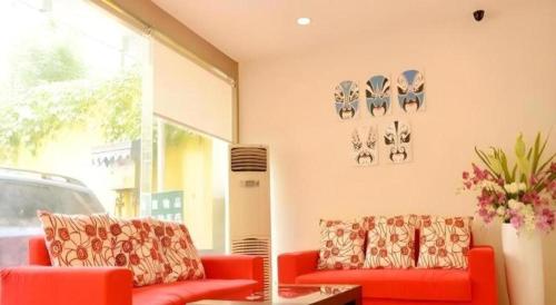 two red couches sitting in a room with a window at 7 Days Inn Chengdu Sichuan University South Railway Station in Chengdu