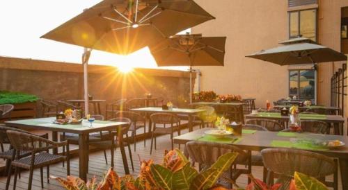 a restaurant with tables and chairs with the sun shining at Hampton by Hilton Zhuhai Doumen in Zhuhai