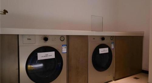 two washing machines in a room with signs on them at Echarm Hotel Jinan Railway Station Daming Lake in Jinan