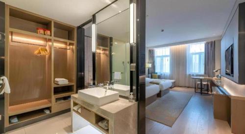 a bathroom with a sink and a large mirror at Echarm Hotel Jinan Railway Station Daming Lake in Jinan