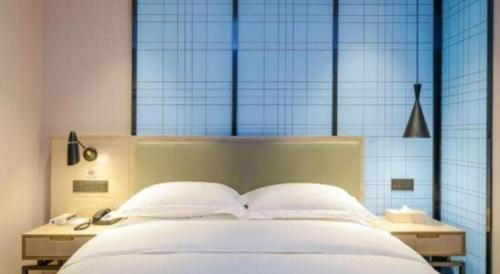 a bedroom with a white bed with a large window at Echarm Hotel Jinan Railway Station Daming Lake in Jinan