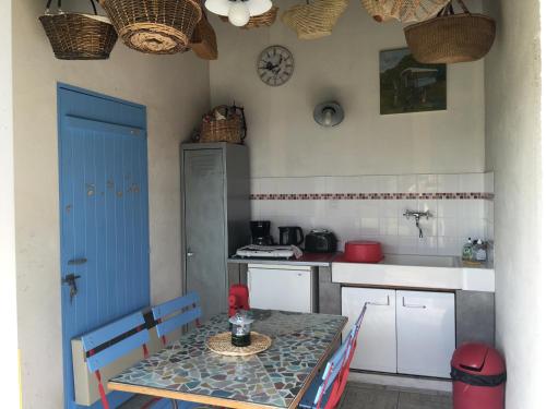 a kitchen with a table and a blue door at La Roulotte des Amis in Ousson-sur-Loire
