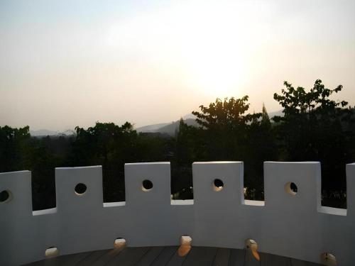 a white fence with holes in it with the sunset at Banrai Pornsawun in Ratchaburi