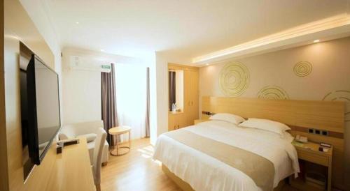 a bedroom with a bed and a flat screen tv at GreenTree Inn Qingyuan Qinghe Avenue Branch in Qingyuan