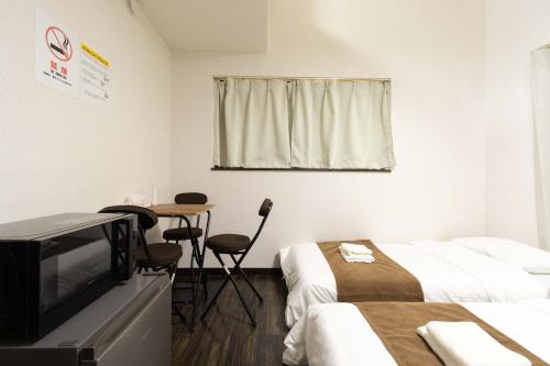 a room with two beds and a tv and a table at Befu Good Place House in Fukuoka