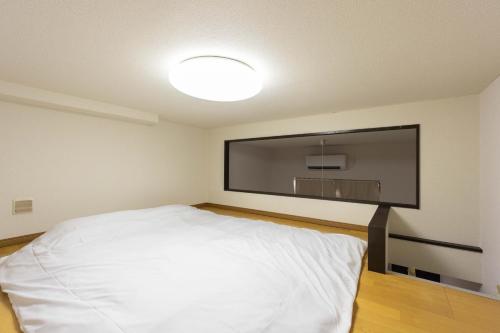 a bedroom with a large flat screen tv on the wall at Befu Good Place House in Fukuoka