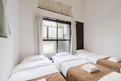 four beds lined up in a room with a window at Befu Good Place House in Fukuoka