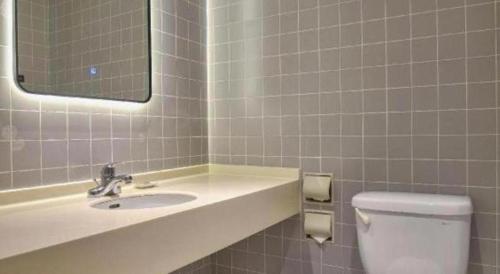 a bathroom with a sink and a toilet and a mirror at Jinjiang Inn Taizhou Huangyan Jiufeng Park in Daidong