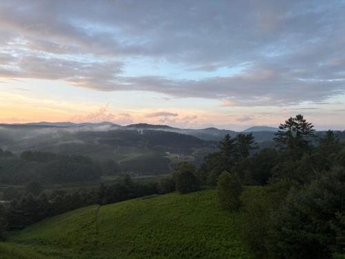 a view of a green hill with the sunset in the background at Chasing Clouds Cabin in Todd