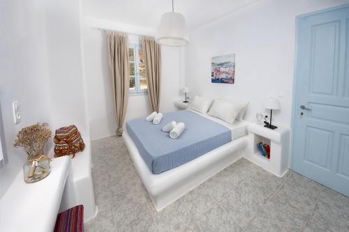 a white bedroom with a blue bed with pillows at Glaros Hotel (By The Sea) in Ios Chora