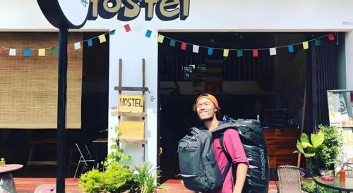 a man with a backpack standing in front of a store at Oldie and Sleepy Hostel in Udon Thani