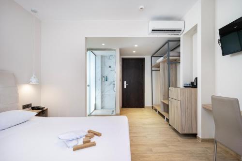 a bedroom with a white bed with a wooden floor at Sonia Hotel & Suites in Kos Town