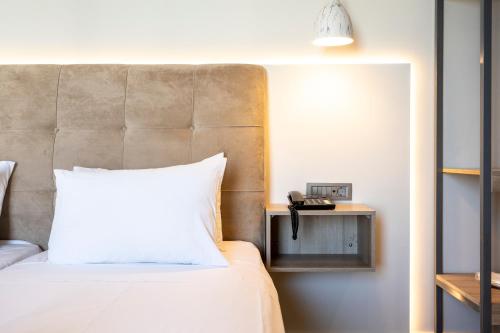 a bedroom with a bed with a white pillow at Sonia Hotel & Suites in Kos Town