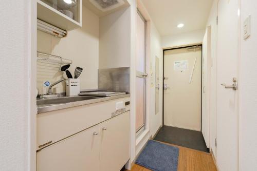 a kitchen with white cabinets and a sink and a door at Minami-Ohashi Good Place House in Fukuoka