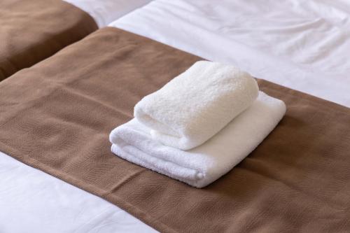 a stack of towels sitting on a bed at Minami-Ohashi Good Place House in Fukuoka