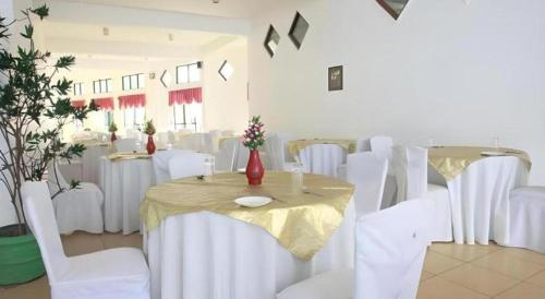 a room with white chairs and a table with a yellow table cloth at Hotel Uva Rest Sanasta in Badulla