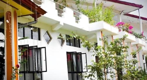 a white building with plants on the balconies at Hotel Uva Rest Sanasta in Badulla